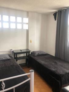 Zimmer mit 2 Betten, einem Tisch und einem Fenster in der Unterkunft Hotelito Ejido de la 10 in Puebla