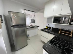 a kitchen with a stainless steel refrigerator and white cabinets at Apartamento quarteirão da praia (Boqueirão) in Santos +9 photos