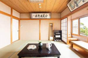 a living room with a table in a room with windows at 熱海網代 太平洋一望和式貸切一軒家 庭でバーベキュー in Ajiro