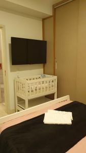1 dormitorio con TV de pantalla plana en la pared en Resort Itanhaém - Pé na areia, en Itanhaém
