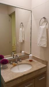uma casa de banho com um lavatório e um espelho em Resort Itanhaém - Pé na areia em Itanhaém