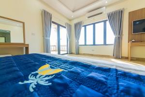 a bedroom with a bed with a blue comforter at Hon Dau Resort in Ðố Sơn