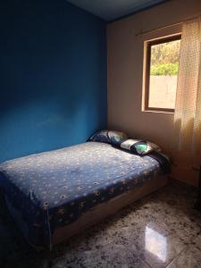 ein kleines Bett in einem blauen Zimmer mit Fenster in der Unterkunft Villas Norita in Ibarra