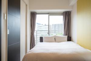 ein Schlafzimmer mit einem Bett und einem großen Fenster in der Unterkunft Residence Hotel Hakata 8 in Fukuoka