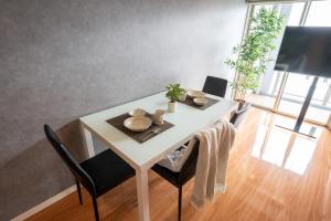 a dining room table and chairs with a white table and a tablewered at Residence Hotel Hakata 8 in Fukuoka