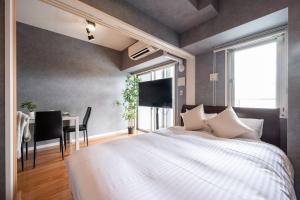 ein Schlafzimmer mit einem großen weißen Bett und einem Tisch in der Unterkunft Residence Hotel Hakata 8 in Fukuoka