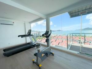 un gimnasio con cinta de correr y una gran ventana en Bayu Apartment Services en Kuah