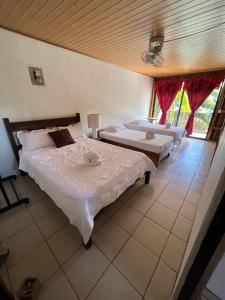 2 camas en un dormitorio con cortinas rojas en Tortuguero Hill Rooms en Tortuguero