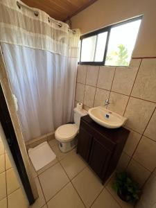 uma casa de banho com um WC, um lavatório e uma janela em Tortuguero Hill Rooms em Tortuguero
