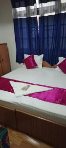 Un dormitorio con una cama con sábanas y almohadas púrpuras. en HOTEL WAYSIDE, en Gangtok