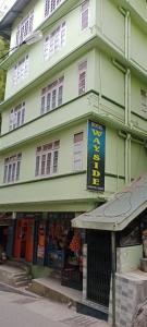 un edificio verde con un cartel delante en HOTEL WAYSIDE, en Gangtok