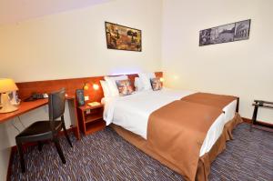 a hotel room with a bed and a desk at Hôtel du Fort in Meulan