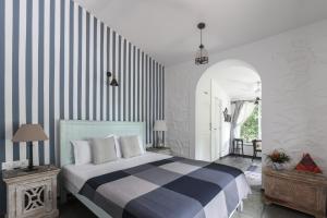 a bedroom with a bed with a striped wall at StayVista at Vanya Farms - Orchard Villa with Rustic Vintage interiors & Table Tennis table in Alibag