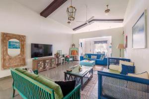 a living room with blue furniture and a tv at Vanya Farms by StayVista - Orchard villa with rustic vintage interiors & a table tennis table in Alībāg