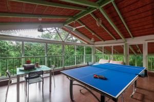a screened in porch with a ping pong table at Vanya Farms by StayVista - Orchard villa with rustic vintage interiors & a table tennis table in Alībāg