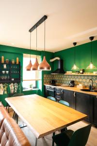 een keuken met een houten tafel en groene muren bij Leaf Apartment - Aviatiei Home in Boekarest