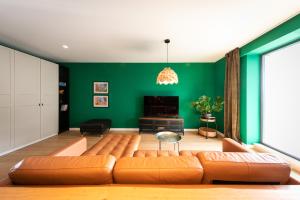 een woonkamer met een bank en een groene muur bij Leaf Apartment - Aviatiei Home in Boekarest