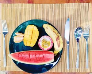 a plate of fruit on a table with fork and knife at GlenMyu Estate in Haputale