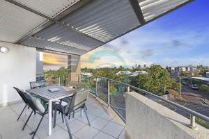 patio con mesa y sillas en el balcón en Zen on Stuart: 3-BR Penthouse Pad + Pool + BBQ, en Stuart Park