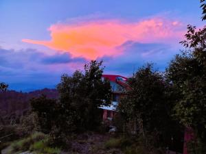 Un nuage rose dans le ciel au-dessus d'une maison dans l'établissement Quiet Place Himalayas, à Mukteswar