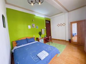 a bedroom with a blue bed with a green wall at Anh Hào Hotel in Da Lat