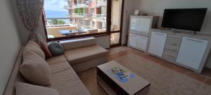 a living room with a couch and a flat screen tv at Cozy apartment with sea view in Pomorie