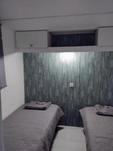 1 dormitorio con 2 camas y pared cubierta de papel pintado en Mobil home les pieds dans l'eau et Gr34, en Ambon