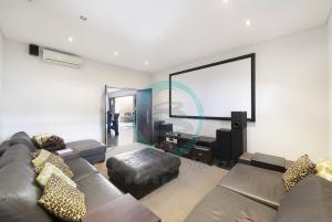 Zen Bayview Bliss: Luxury Marina Mansion في Stuart Park: غرفة معيشة بها أريكة وشاشة كبيرة