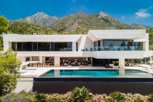 una casa con piscina y montañas en el fondo en Buccara Villa El Nido, en Marbella