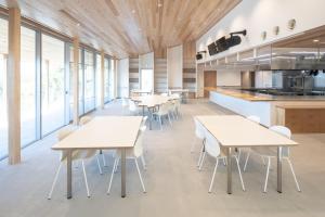 a cafeteria with white tables and chairs and windows at Teshima ESPOIR PARK in Ieura