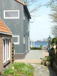 a gray house with a pathway next to the water at B&B It Lytshûs in Earnewâld