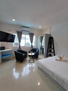 a bedroom with a bed and chairs and a television at The Villa Residences Resort in Patong Beach