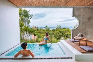 une femme et un enfant dans une piscine dans une maison dans l'établissement Myth Koh Larn resort bar and bistro, à Ko Larn