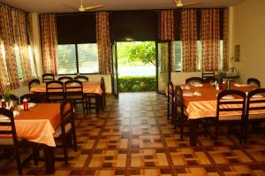 comedor con mesas y sillas y ventanas grandes en Motibagh Resort, en Sawāi Mādhopur