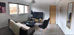 ein Wohnzimmer mit einem Sofa und einem TV in der Unterkunft Bel appartement cosy très calme avec parking privé in Templemars