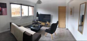 a living room with a couch and a television at Bel appartement cosy très calme avec parking privé in Templemars