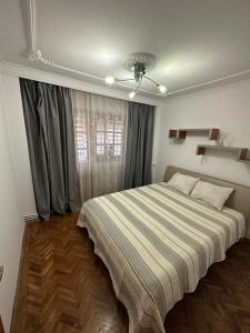 a bedroom with a large bed with a striped blanket at Bulevard Residence in Drobeta-Turnu Severin