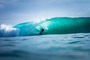 Un uomo che cavalca un'onda su una tavola da surf nell'oceano di Sumatra Surf Resort a Biha