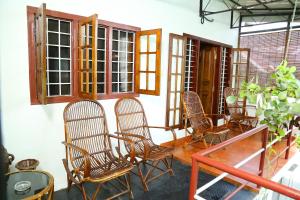 a porch with chairs and a table and windows at Walton's Homestay, Fort Cochin in Fort Kochi