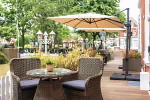 um pátio com uma mesa, cadeiras e um guarda-sol em Hotel Haus am Park em Borkum