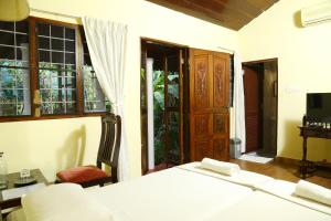 a bedroom with a bed and a tv and windows at Walton's Homestay, Fort Cochin in Fort Kochi