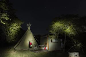 a tent with a table in front of a house at night at Simbonga Game Reserve & Sanctuary in Thornhill