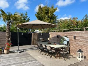 a table and chairs under an umbrella on a deck at NEW - LITTLE IBIZA, on a lake near Amsterdam, with HOT TUB! in Vinkeveen