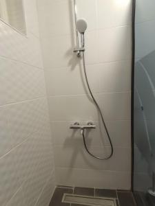 a shower with a hose in a white tiled bathroom at Red Square Apartment in Pirot +27 photos