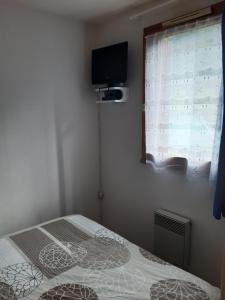 a bedroom with a bed and a window with a television at Appartement entre thermes et montagne in Luchon