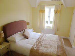 Pump Cottage في ويماوث: غرفة نوم بسرير وملاءات بيضاء ونافذة