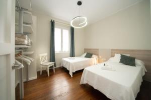 Biały pokój z 2 łóżkami i krzesłem w obiekcie Apartamento con garaje en el centro de Zumaia w mieście Zumaia