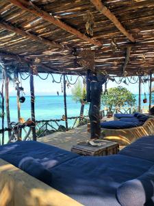 una camera con letti blu e l'oceano sullo sfondo di Promised Land Lodge a Kizimkazi
