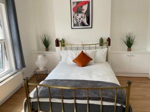 a bedroom with a bed with white sheets and an orange pillow at Large, Bright and Spacious 3 Bed Flat in London in London