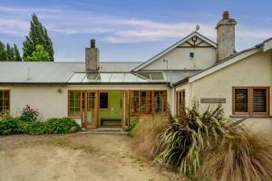 une vieille maison blanche avec une porte verte dans l'établissement Glendhu Station Homestead - Glendhu Bay Home, à Glendhu